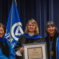 Provost Mili and President Mantella smile for picture with woman holding certificate on stage